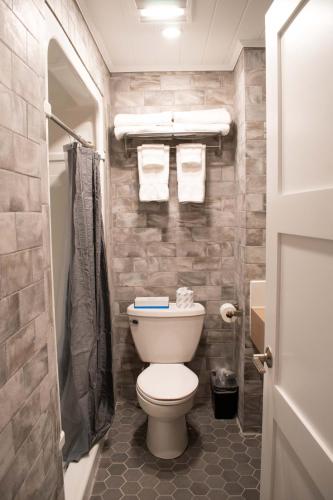 a bathroom with a toilet and a shower with towels at Colonial Hotel & Suites in Grand Bend