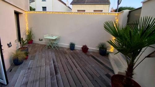 eine Terrasse mit Topfpflanzen und Licht an einem Gebäude in der Unterkunft Au 10 Bed & Breakfast in Luisant