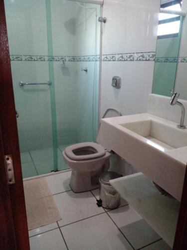uma casa de banho com um WC, um chuveiro e um lavatório. em Apartamento 02 em Garopaba