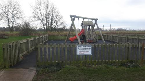 a playground behind a fence with a sign on it at Coastal Annex at Saltfleet in Louth