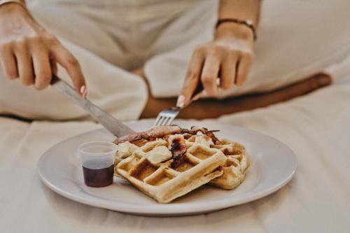 a person eating a plate of waffles and syrup at B's Suites Mérida in Mérida