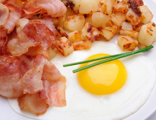 a white plate topped with eggs, sausage and bacon at Holiday Inn Lethbridge, an IHG Hotel in Lethbridge