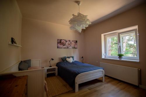 a bedroom with a bed and a window and a chandelier at Szélcsend Apartman in Balatonföldvár