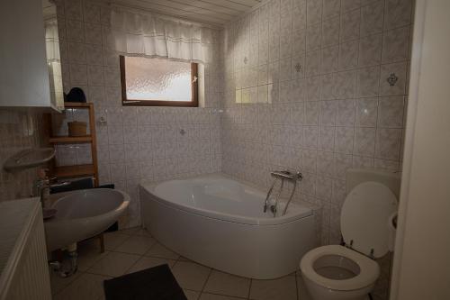 y baño con bañera, aseo y lavamanos. en Szélcsend Apartman, en Balatonföldvár
