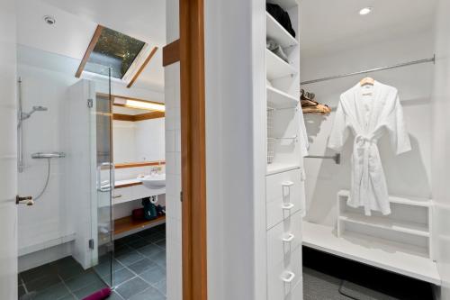 uma casa de banho com uma cabina de duche ao nível do chão e um roupão branco em Brunswick Lodge - Luxury - Central Queenstown em Queenstown