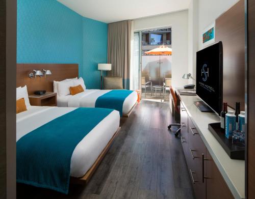 a hotel room with two beds and a flat screen tv at Shore Hotel in Los Angeles