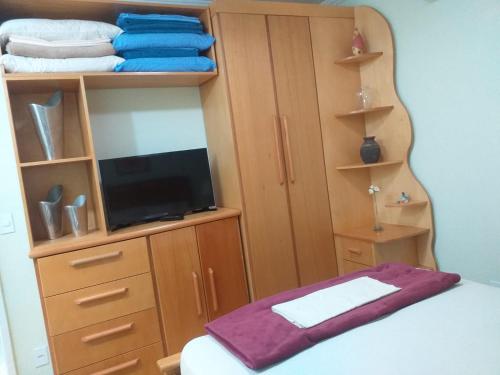 a bedroom with a bed and a dresser with a tv at Apartamento Paraíso das Dunas em Cabo Frio in Cabo Frio