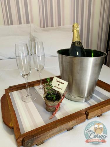 a tray with a bottle of wine and glasses on a bed at Casa da Coruja in Rio de Janeiro