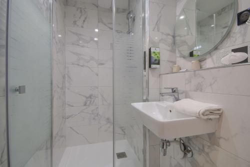 a white bathroom with a shower and a sink at Sure Hotel by Best Western Reims Nord in Reims