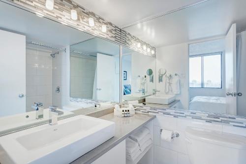 a white bathroom with a sink and a large mirror at LaCité Cozy Apartment Close to Central Montreal in Montréal