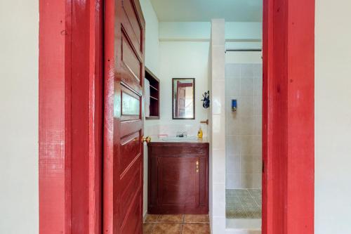 a red door leading to a bathroom with a sink at Willow 2 at Island Cabanas Gold Standard Certified in Caye Caulker