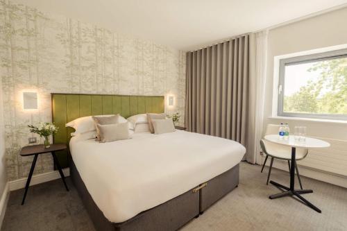 Un dormitorio con una gran cama blanca y una mesa en The Hoban Hotel Kilkenny en Kilkenny