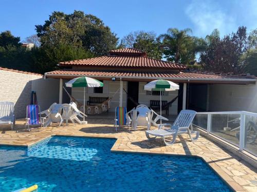 a pool with chairs and umbrellas next to a house at RANCHO KWILL in Serra Negra