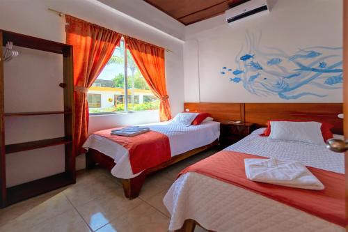 ein Schlafzimmer mit 2 Betten und einem Wandgemälde in der Unterkunft Hotel Coral Blanco with high speed internet Starlink in Puerto Villamil