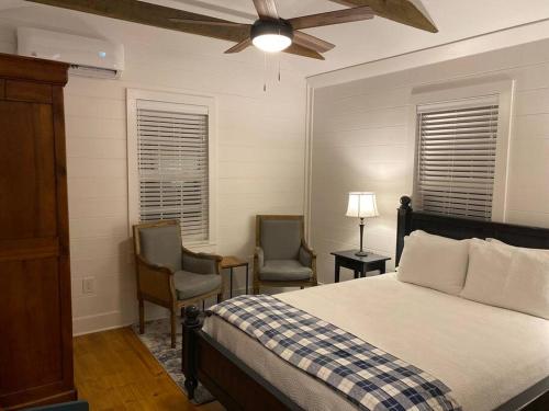a bedroom with a bed and two chairs and a ceiling fan at Cottage in Summerville
