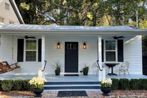 a white house with a porch with a black door at Cottage in Summerville