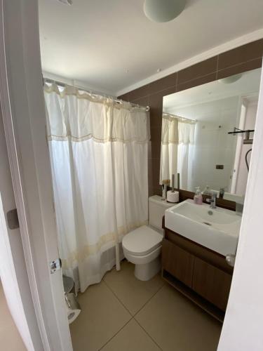 y baño con aseo, lavabo y espejo. en Departamento junto a la playa "Marina Horizonte", en Coquimbo