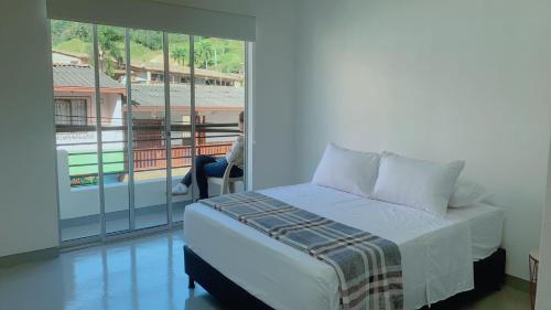 a person sitting in a chair in a room with a bed at Aloja-T en Apartamento amoblado 5 con balcón en Ciudad Bolivar in Ciudad Bolívar
