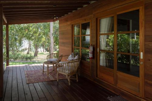 un porche de madera con 2 sillas y una puerta en Amaya Boutique Resort en Srithanu