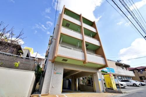 un edificio en una calle con coches aparcados delante en はなハウス 2F en Ginowan