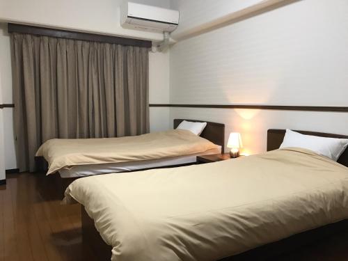 a hotel room with two beds and a window at Weekly & Monthly City Inn Kokura in Kitakyushu