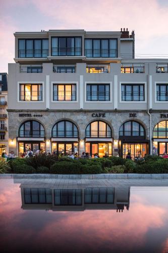un bâtiment avec une réflexion dans une masse d'eau dans l'établissement Hôtel Le Café de Paris, à Biarritz