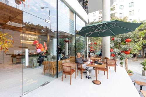 a man sitting at a table with an umbrella at 22Land Hotel & Residence in Hanoi