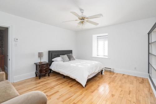 a white bedroom with a bed and a ceiling fan at Centennial 6-Bedroom Waterfront Palace Sleeps 14 in Montréal