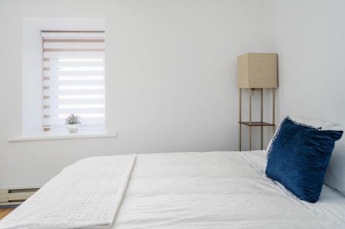 a white bed with a blue pillow and a window at Centennial 6-Bedroom Waterfront Palace Sleeps 14 in Montréal