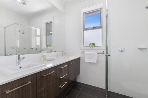 a white bathroom with a sink and a shower at Western Breeze in Port Willunga