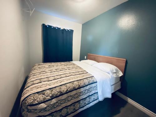 a small bedroom with a bed with a blue wall at Sands Inn in South Gate
