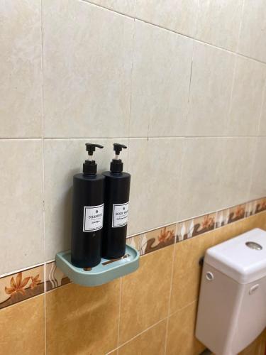 two black bottles on a shelf next to a toilet at Mutiara Chalet Bandar Melaka in Melaka