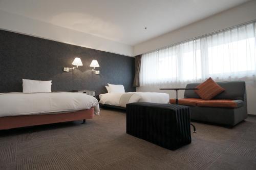 a hotel room with two beds and a chair at Green Rich Hotel Nishitetsu Ohashi Ekimae in Fukuoka