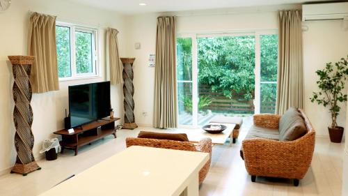 a living room with a couch and a tv at Irie House Motobu in Motobu