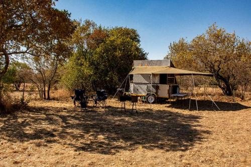 a camper with chairs and a tent in a field at Shamba Yetu Mountain Lodge in Maanhaarrand