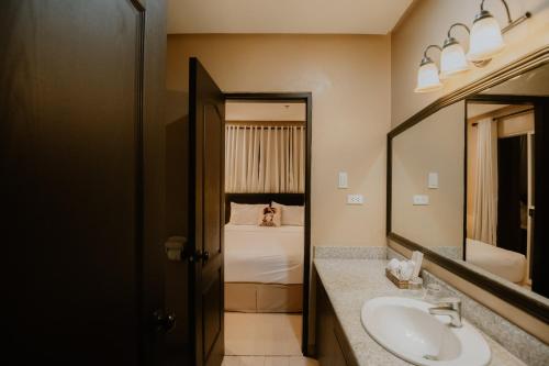 a bathroom with a sink and a mirror and a bed at Sta Barbara Residence Hotel in Cebu City