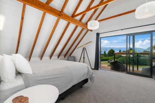 a bedroom with a bed and a large window at Views on Parry - Lake Hāwea Holiday Home in Lake Hawea