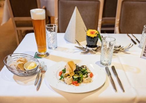 a table with a plate of food and a glass of beer at Romantik Hotel Stryckhaus in Willingen