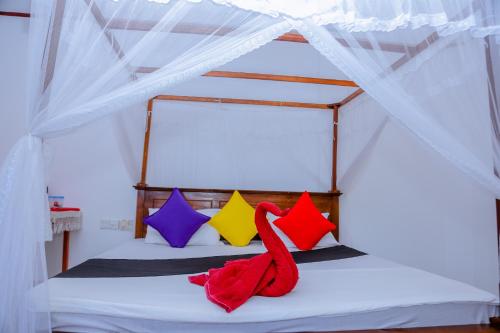 a bed with colorful pillows and a red towel on it at Sajana Ocean Hill in Mirissa