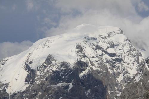 a mountain covered in snow and clouds in the sky at Hotel Genziana in Passo Stelvio