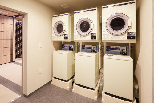 a laundry room with three washers and dryers at Minn Nishi Kasai in Tokyo