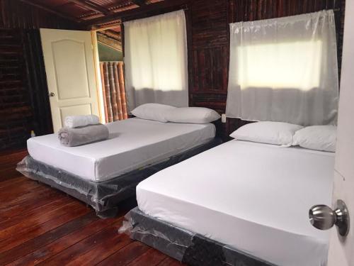 two white beds in a room with wooden floors at Room in Lodge - Family Cabin With River View in Rizaralda