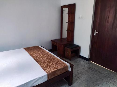 a bedroom with a bed and a table and a door at Schatzi's Hideaway in Tangalle
