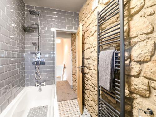 a bathroom with a stone wall and a shower at 3 Sunnyside Terrace in Matlock