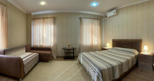 エッセントゥキにあるGuest House Nataliのベッドルーム1室(ベッド1台、ソファ、椅子付)
