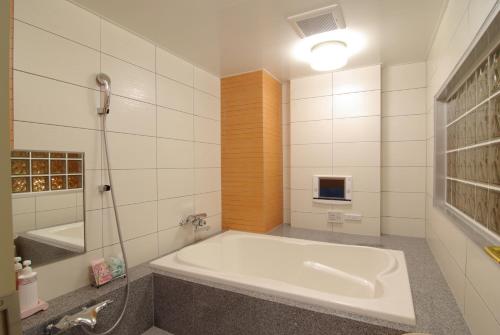 a white bathroom with a tub and a shower at Shonan Sirene (Adult Only) in Hiratsuka