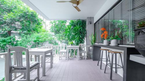 a patio with white chairs and tables on a porch at Yellow Ribbon Hills Boutique Suites in Bangkok