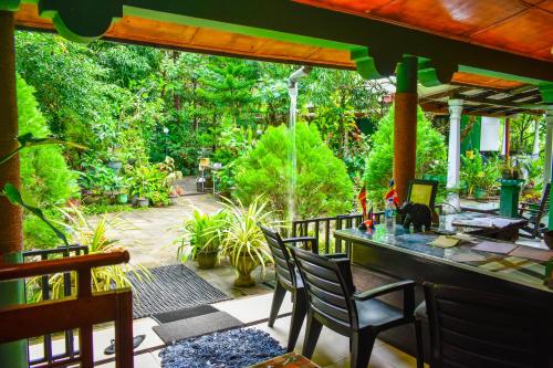 een patio met een tafel, stoelen en bomen bij Sigiri Rock Side Home Stay in Sigiriya