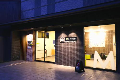 a store front with a m sign in the window at M's Hotel Gojo Odawara in Kyoto