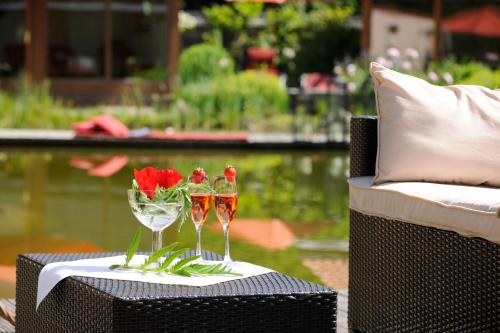 two wine glasses on a table next to a chair at Wellnessgarten-Hotel in Waging am See